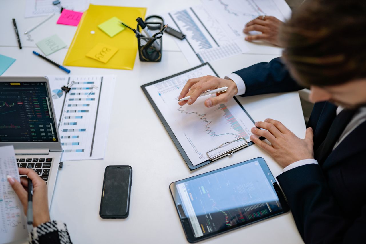 A team examines financial charts and digital data on tablets in an office environment.